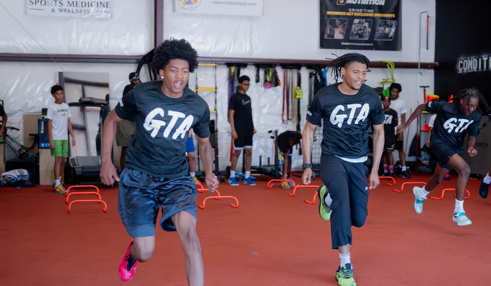 Clock In athletes in Grind Time shirts sprinting across the turf in Portsmouth