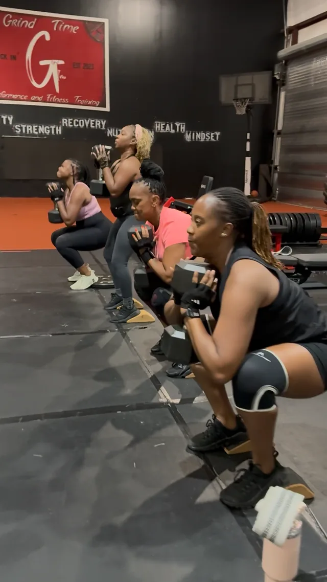 Clock In Q-Fit members doing goblet squats together on the turf