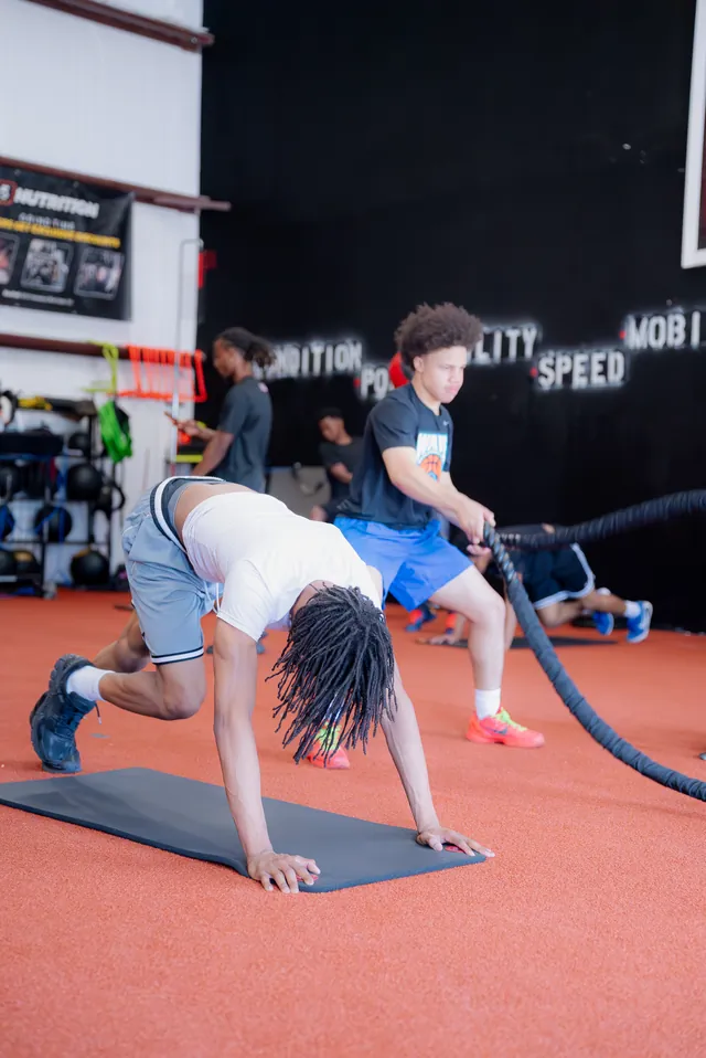 Athletes working battle ropes and crawls on the turf